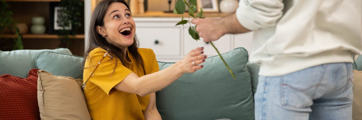 A joyful woman receives a rose, showcasing love and affection in a cozy indoor setting filled with warmth and emotion.